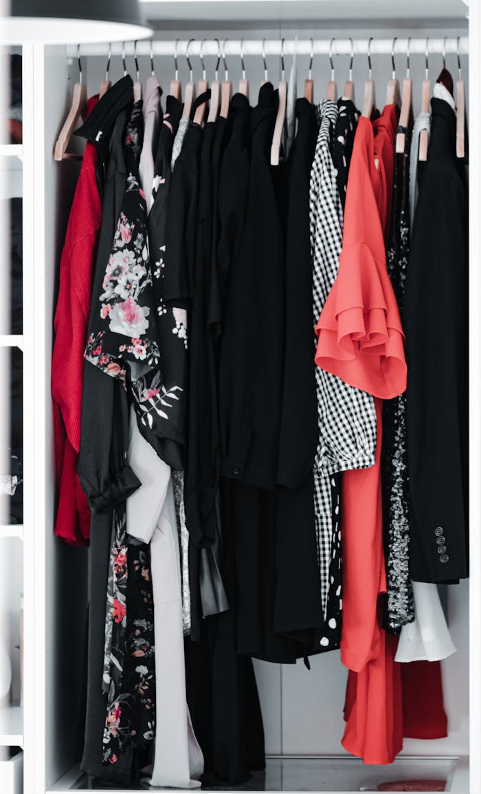 A neatly arranged wardrobe with various styles and patterns of clothing hanging on wooden hangers.